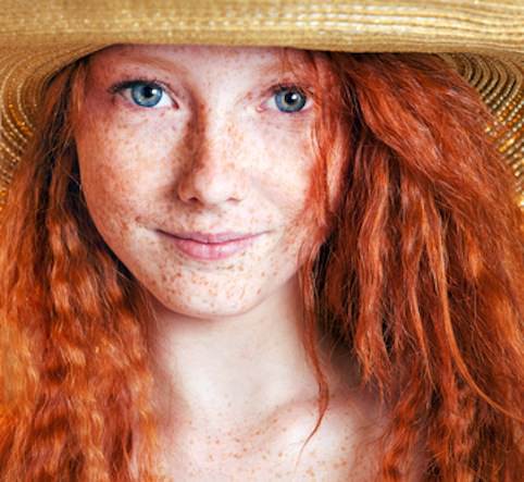 Beautiful freckled young woman wearing straw hat