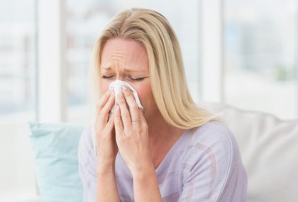 Woman sneezing in tissue in the living room