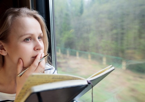 Young woman on a train writing notes